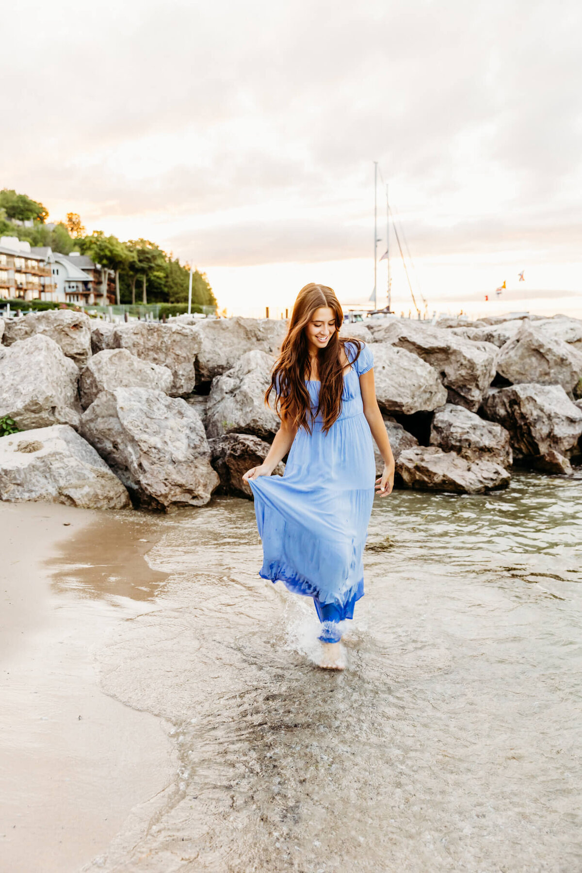 brunette girl kicking up the water as she walks along the beach in Oshkosh