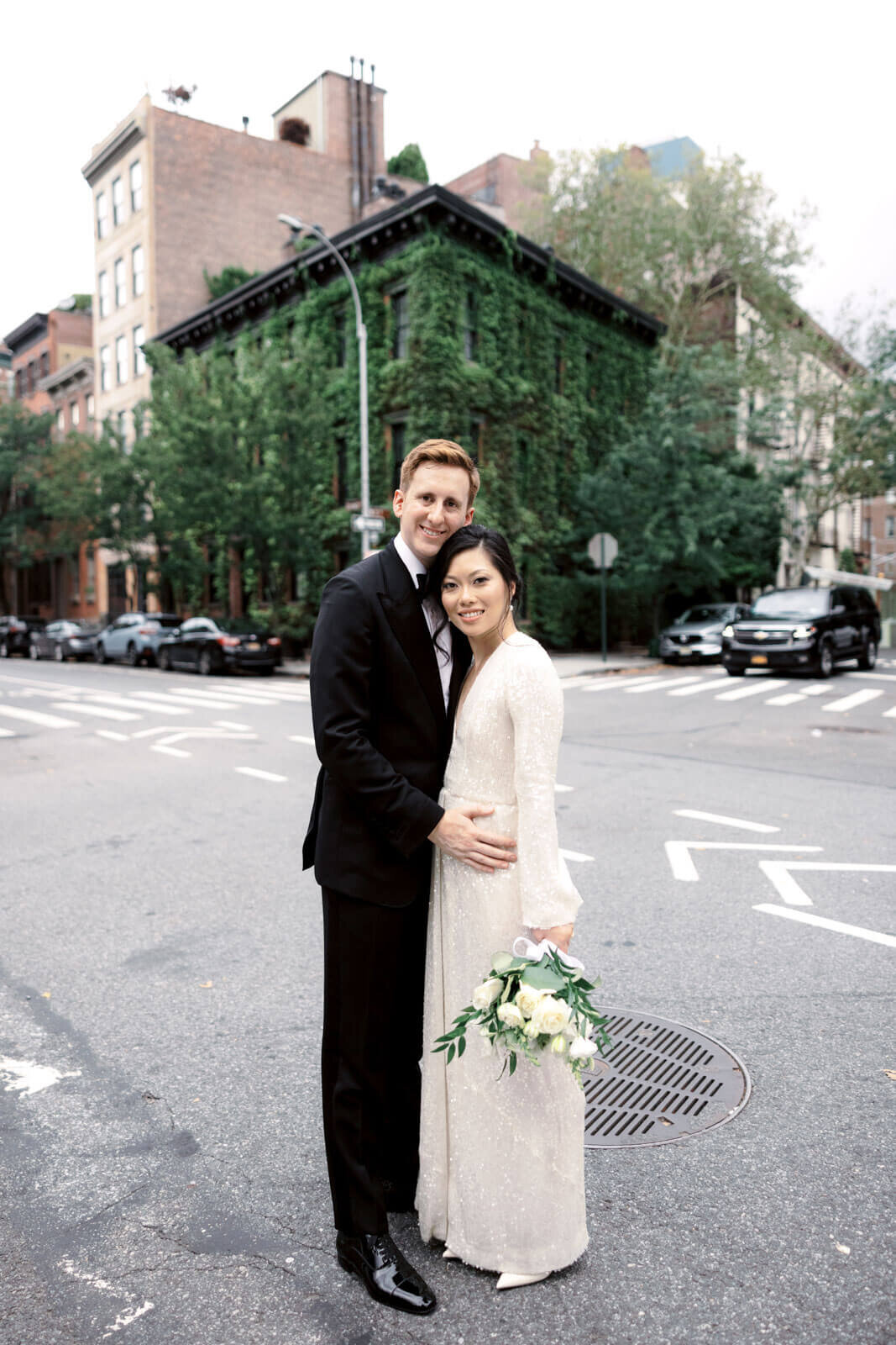 The bride and the groom are standing close to each other at a corner street in West Village, NYC. Image by Jenny Fu Studio