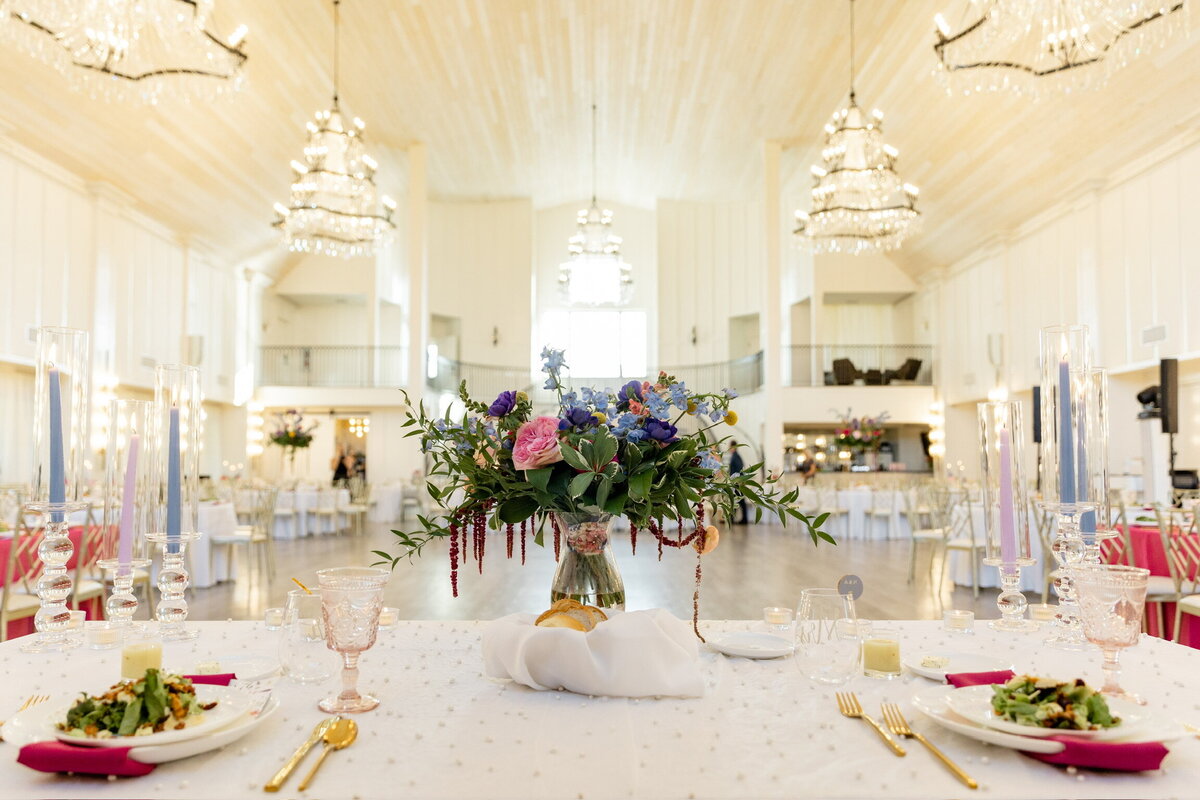 Crystal Chandeliers hang elegantly from ceiling of a beautiful white wedding venue