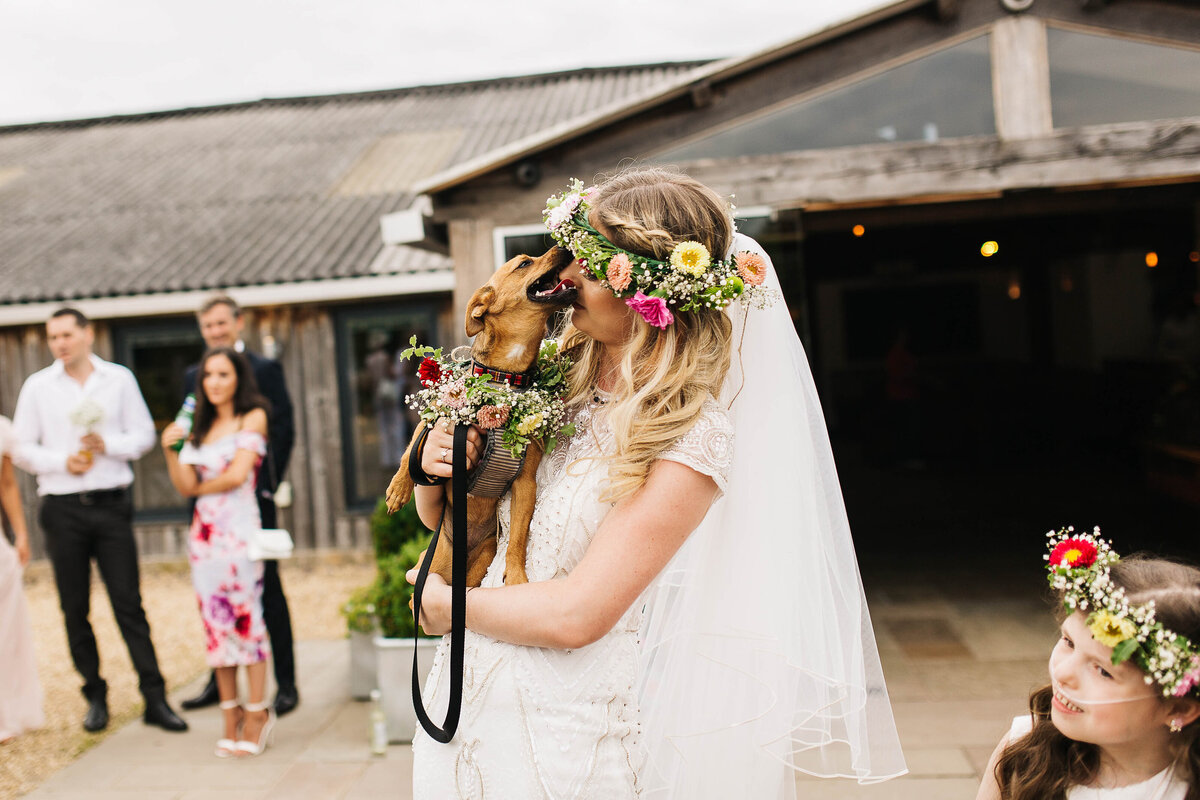 Bride hugging her dog as it nibbles her nose in York