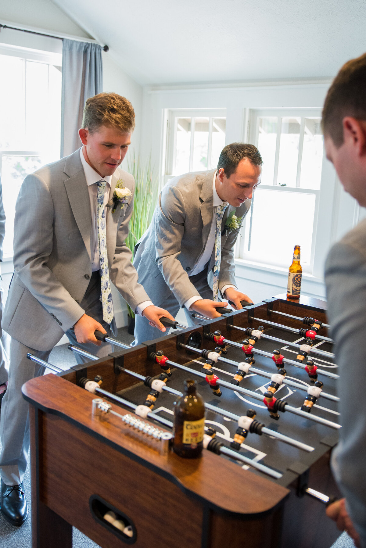 A group of groomsmen play foosball after getting ready on the wedding day.