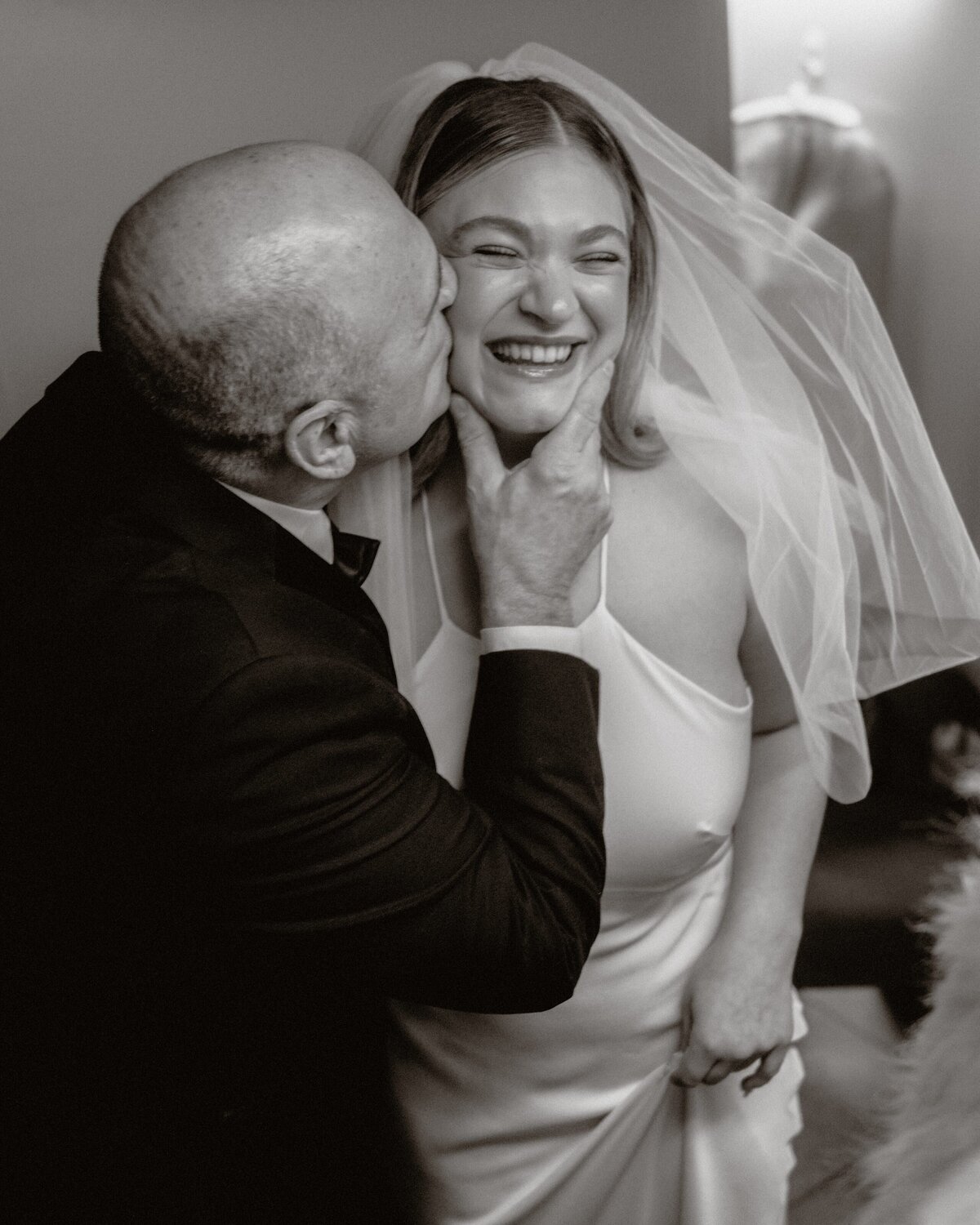 father of the bride kisses bride on the cheek