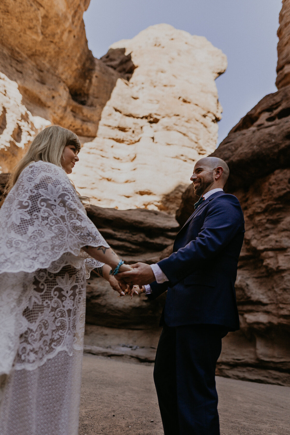 bride and groom standing in a slot canyon holding hands