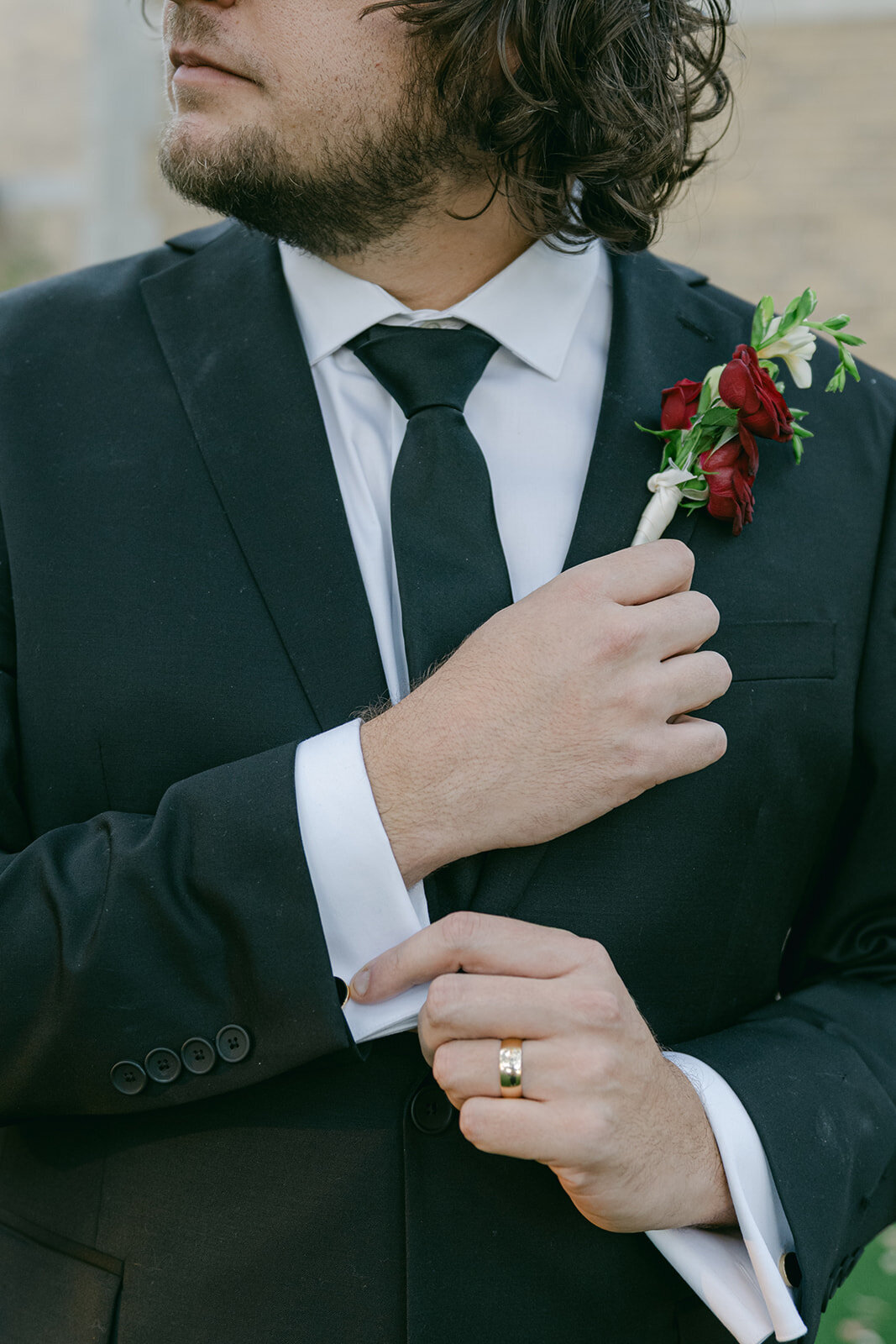 Editorial close-up of red floral boutonnière pinned on groom’s jacket at San Antonio wedding