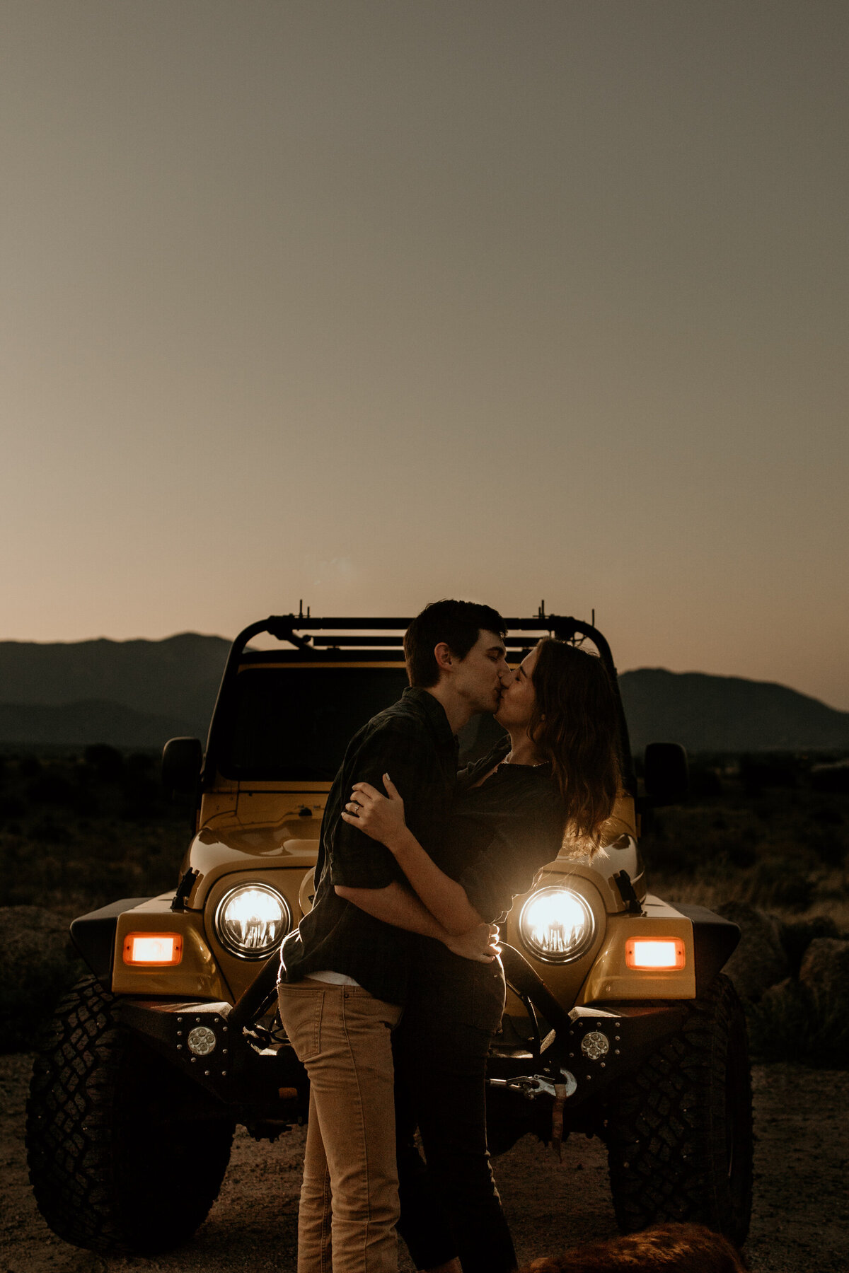 engaged couple kissing in front of jeep at sunrise in Albuquerque