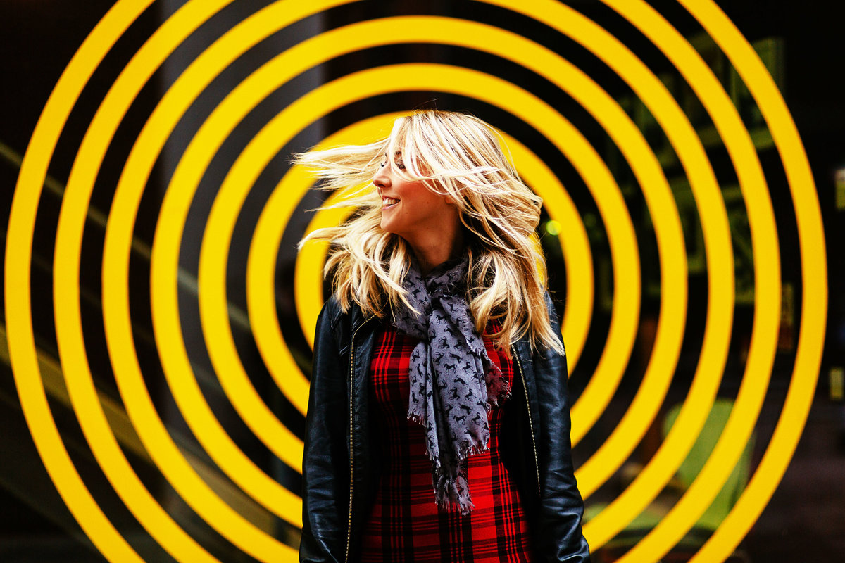 A picture of a girl shaking her hair stood in front of a colourful circle backdrop in Leeds