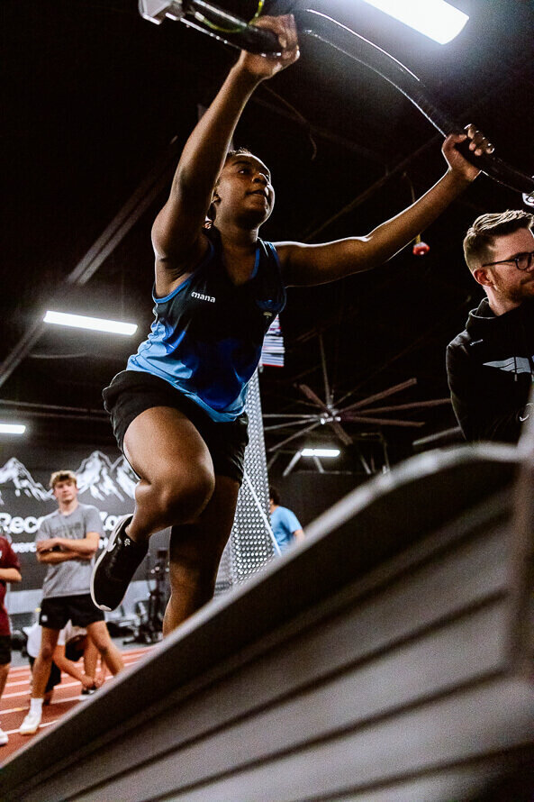 Upward angle of a girl holding onto and running on a treadmill.