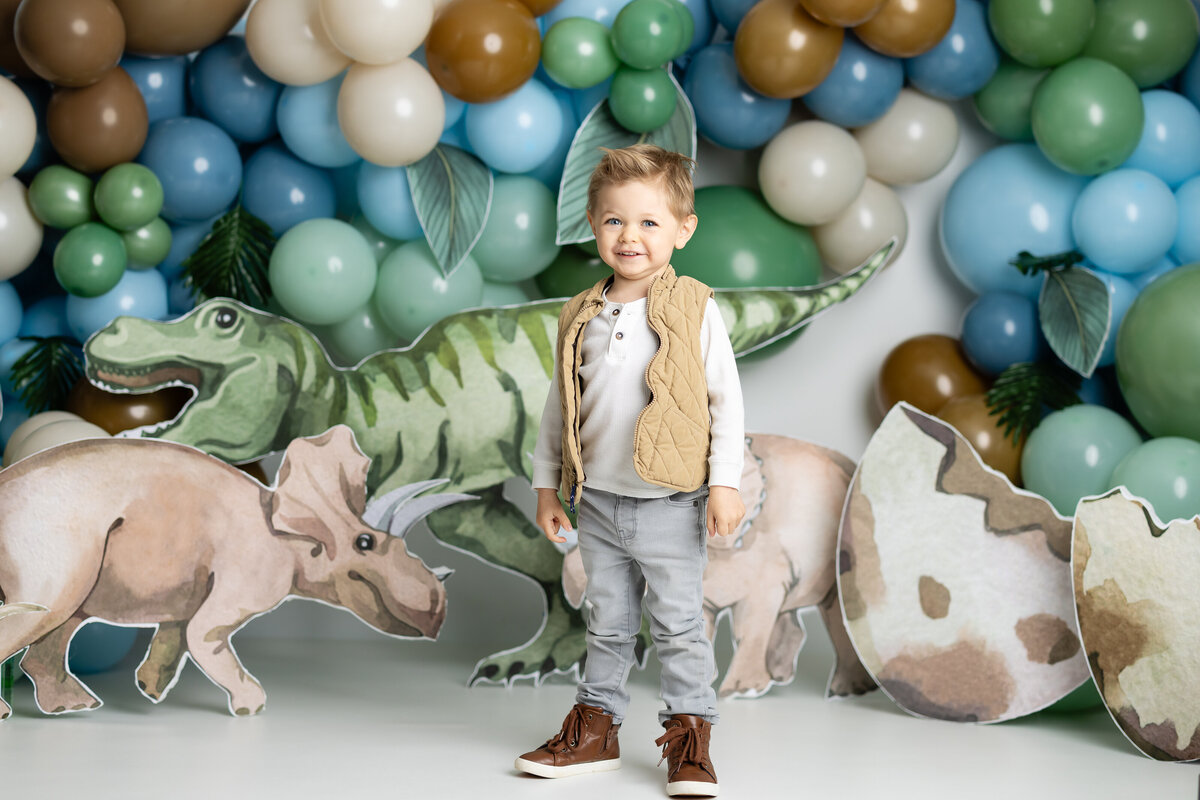 Young boy enjoying a dinosaur-themed birthday session with fun props and decorations, captured in Canton, GA by Victoria Lee Photography.
