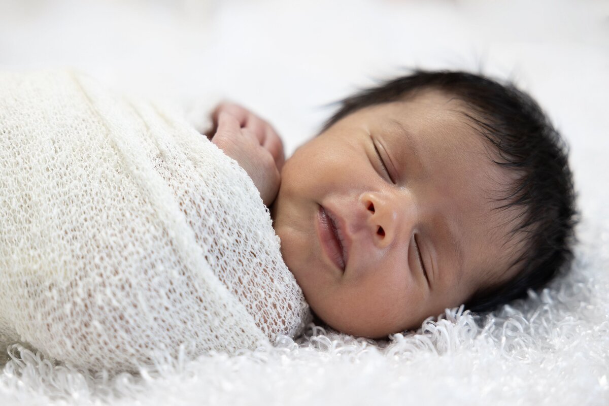 newborn baby in white swaddle