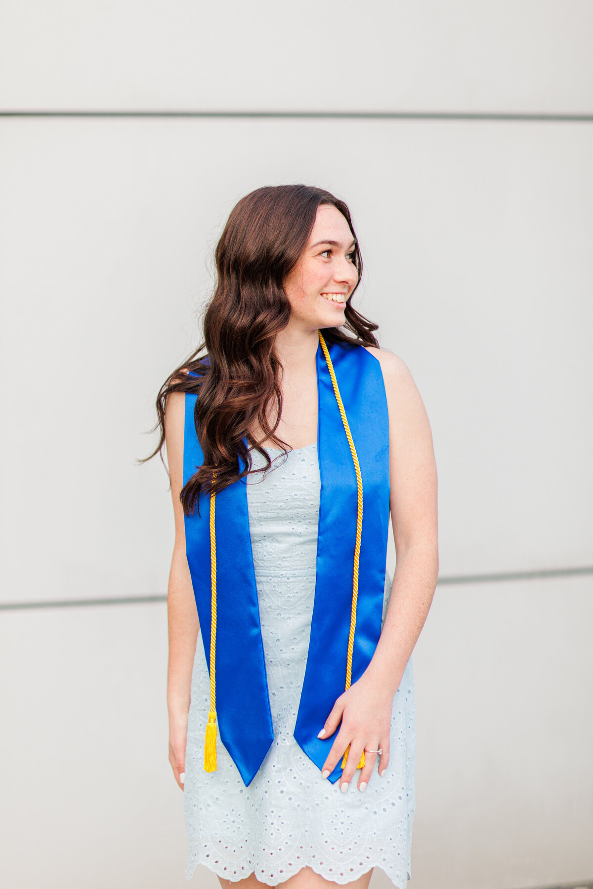 A girl wearing her graduation cords and smiling off camera representing Boston graduation pictures