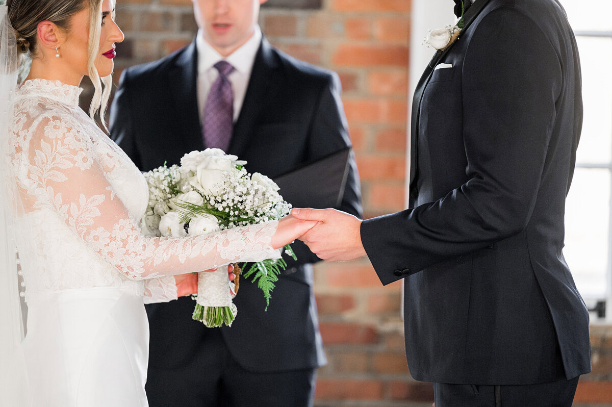 bride and groom holding hands while she also holds bouquet by fox and the fleur florist
