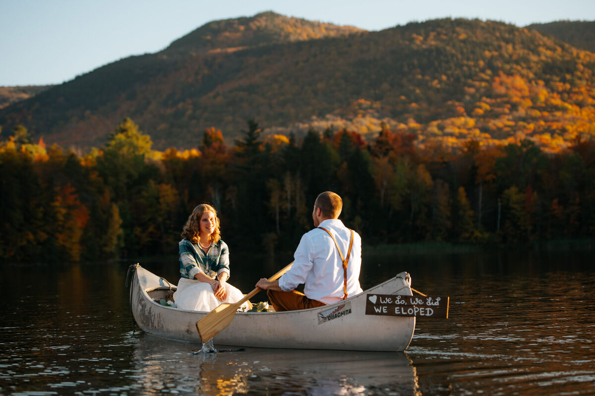 adventure elopement couple in canoe with foliage at chittenden reservoir by mountain top inn in vermont paddling