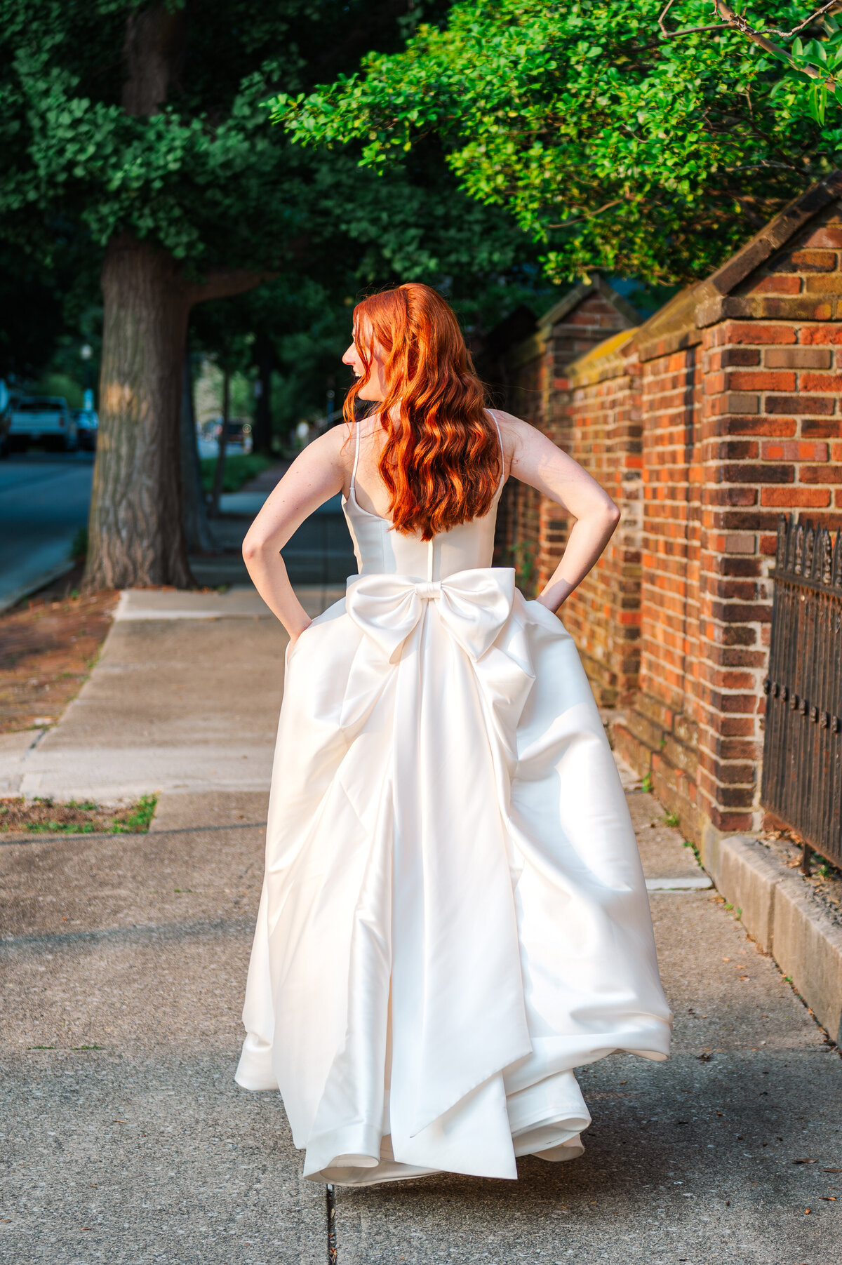 bride running into the golden hour light while showing off a beautiful bow on the back of her dress