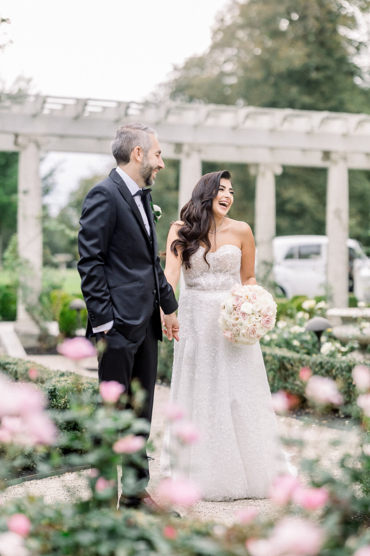 bride and groom laugh candidly in the rose gardens of rosecliff mansion in newport rhode island