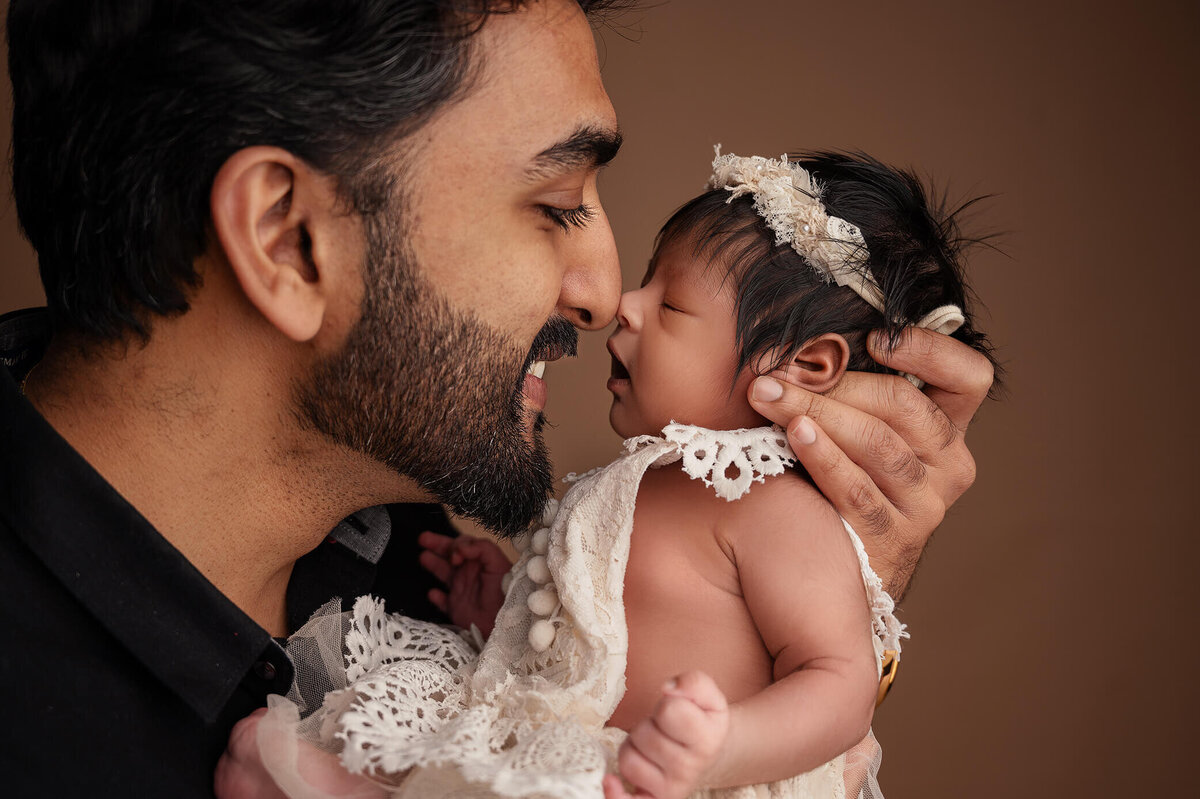 Up close of a new father holding and touching nose to nose his newborn girl at Tamara Danielle's Photography portrait session.