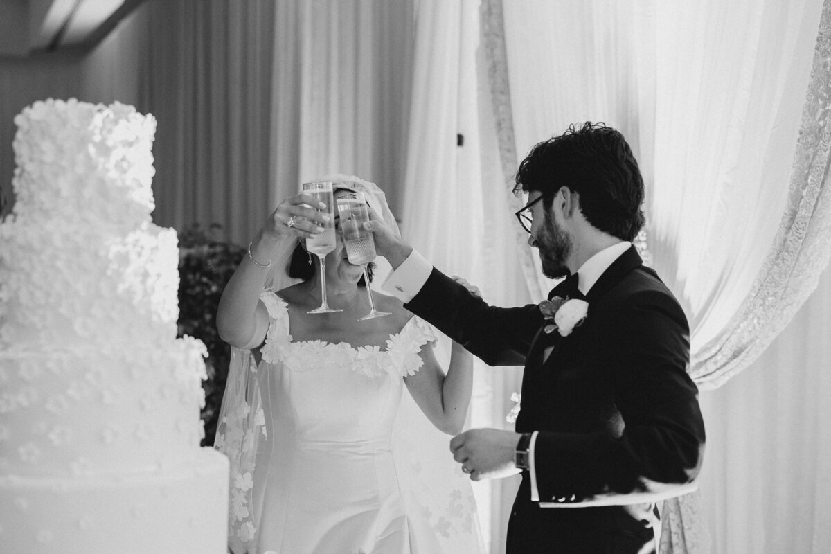 Bride and groom toasting next to a wedding cake