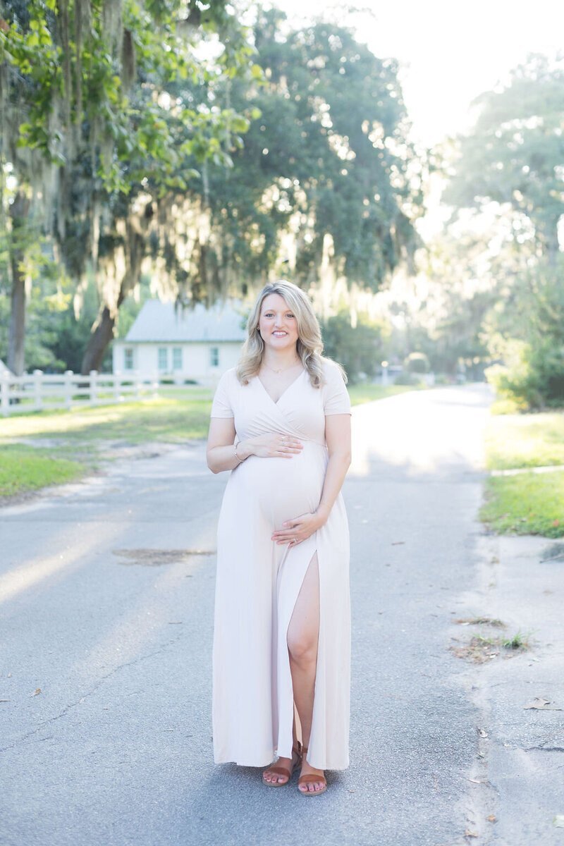 Mother posing in blush maternity dress for photography session in Savannah, GA