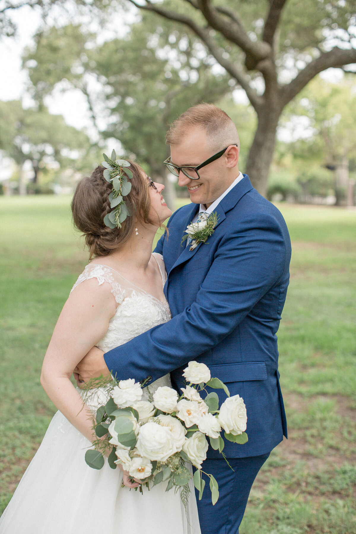 A bride in a floral crown gazes into her grooms eyes as he embraces her