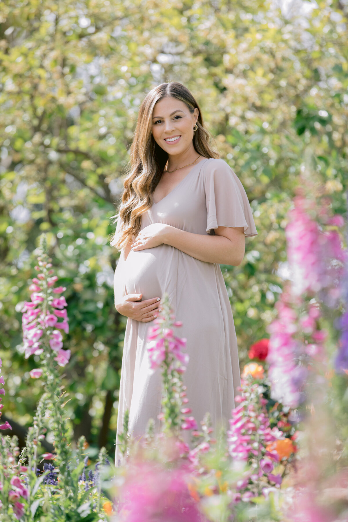 A pregnant woman holding her stomach in a garden area