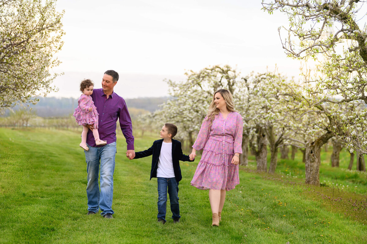 Mom and dad with their sone and daughter walking through the Cherry Blossoms for their family photography session in Burlington, Ontario.