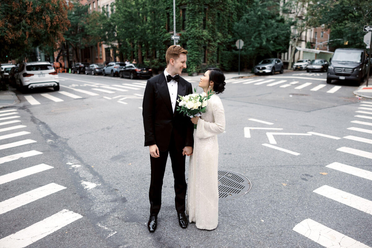 The bride and the groom are romantically staring at each other at a corner street in West Village, NYC. Image by Jenny Fu Studio