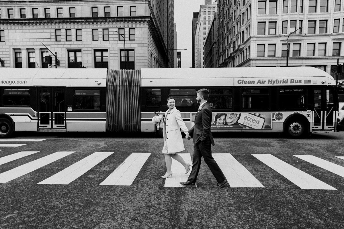 Just Married photo session couple crosses a Chicago street with CTA bus whizzing by in the background