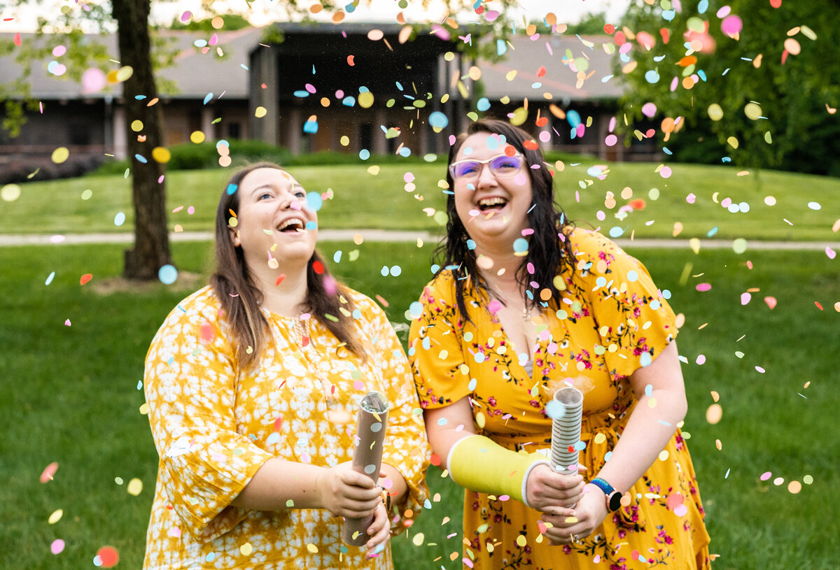 LGBTQ couple, Brianna and Alexa, laugh as they launch confetti cannons at Franklin Park in Columbus, Ohio.