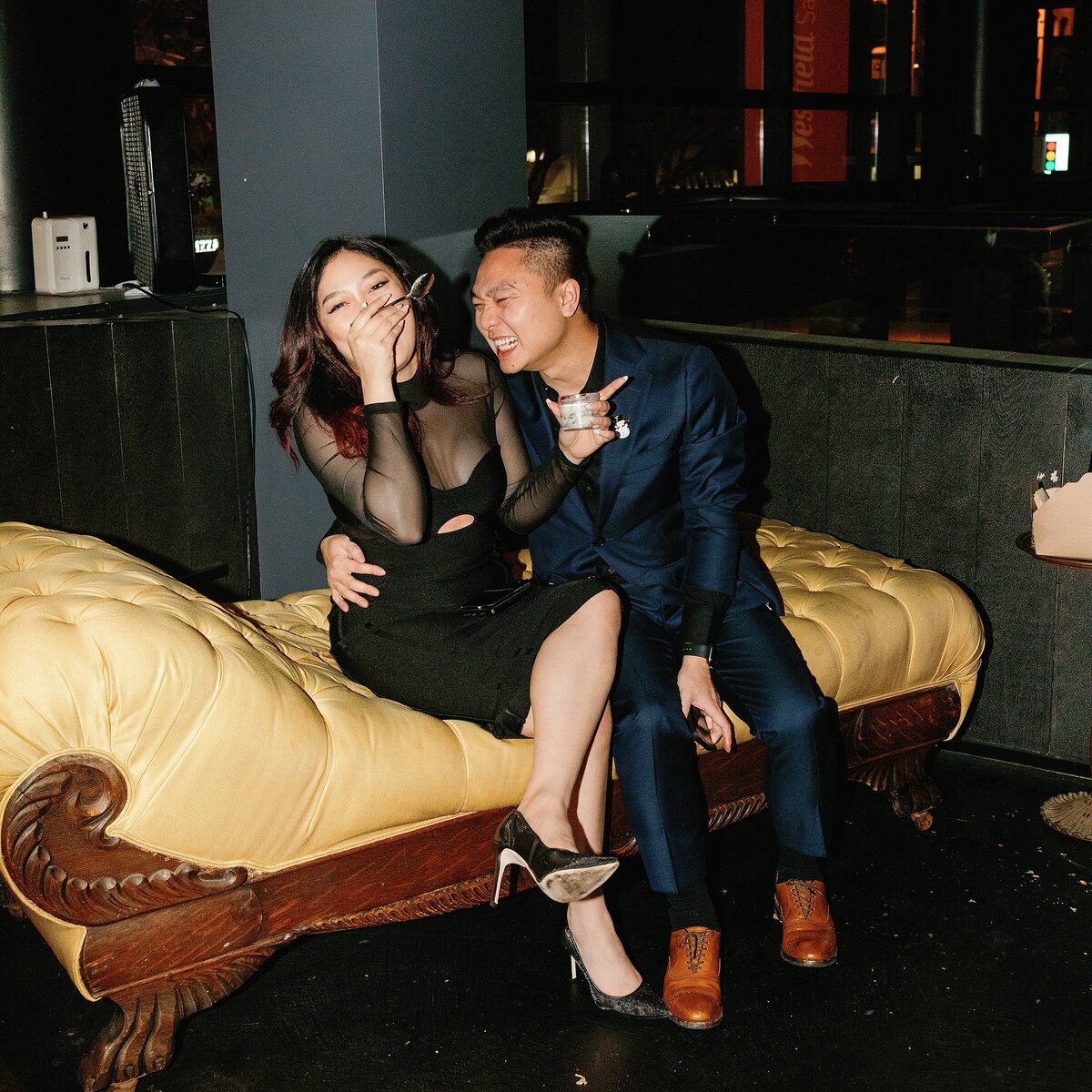 Chic couple laughs hard while cozied up on a chaise lounge