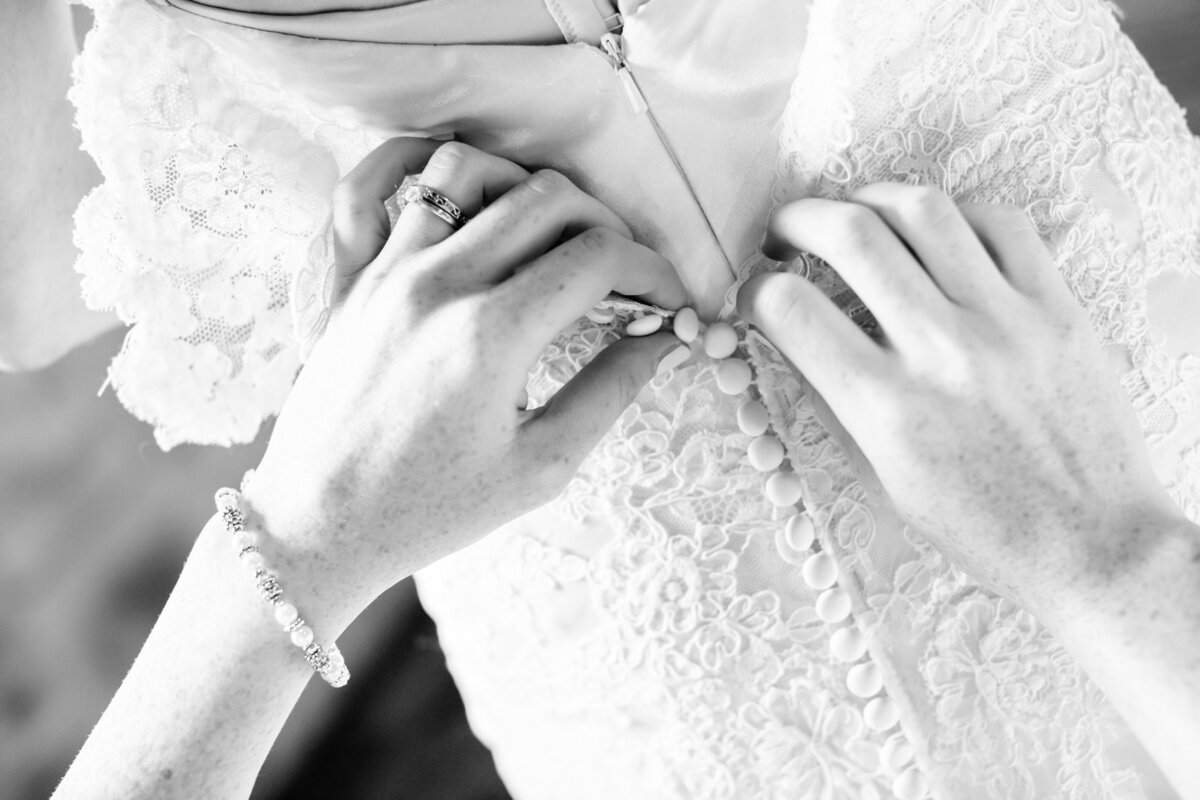 black and white of hands buttoning wedding dress in Austin Texas