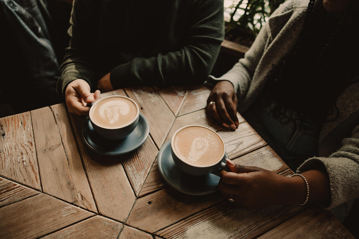 Two people sitting at a table with coffees 