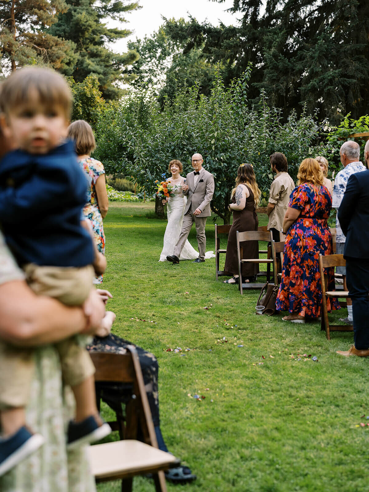 A bride and her father walking up the aisle at a backyard wedding. 