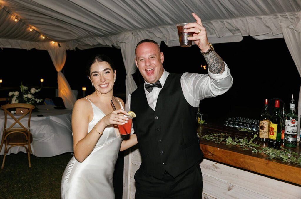 The newlyweds raise their drinks in celebration, enjoying their wedding night with friends and family. Captured by Claudia Amalia Photography, a destination wedding photographer in the Florida Keys.