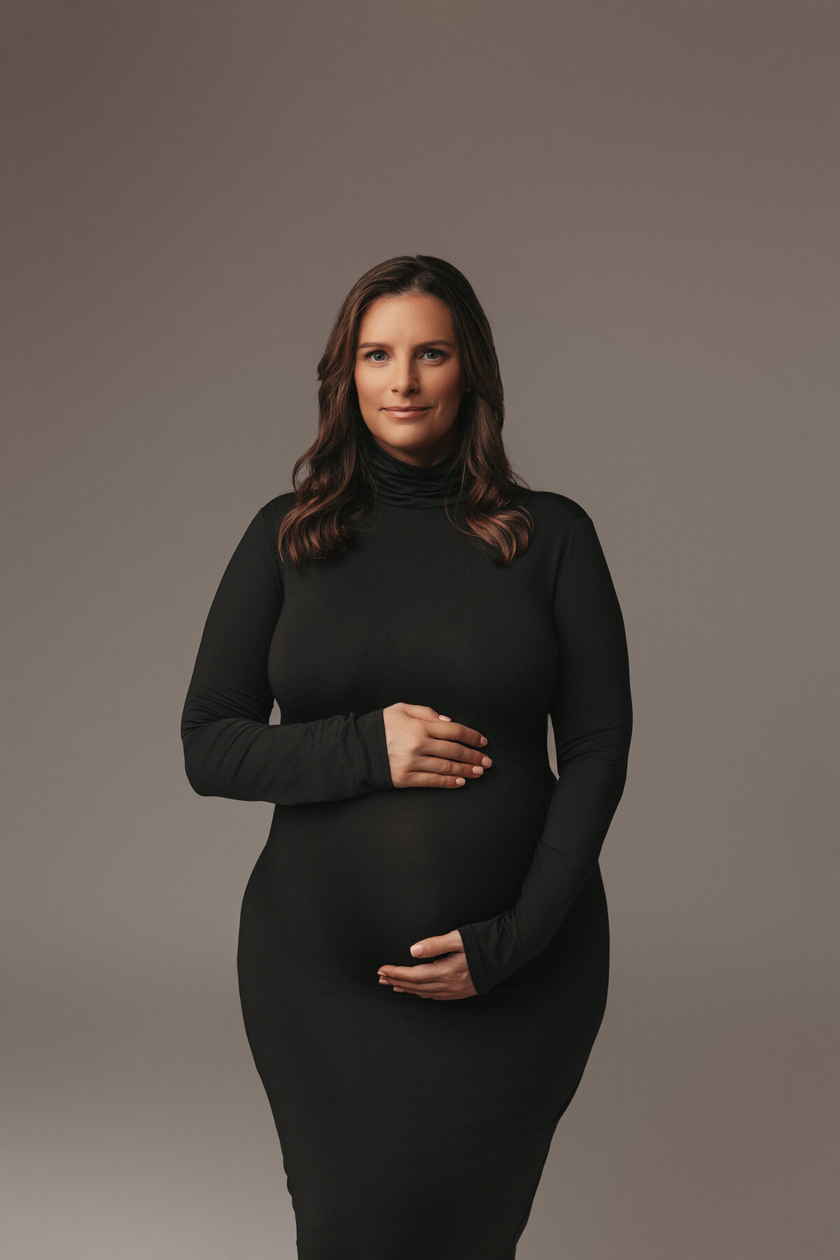 plus size pregnant woman posing for maternity photographer in phoenix in black turtle neck dress