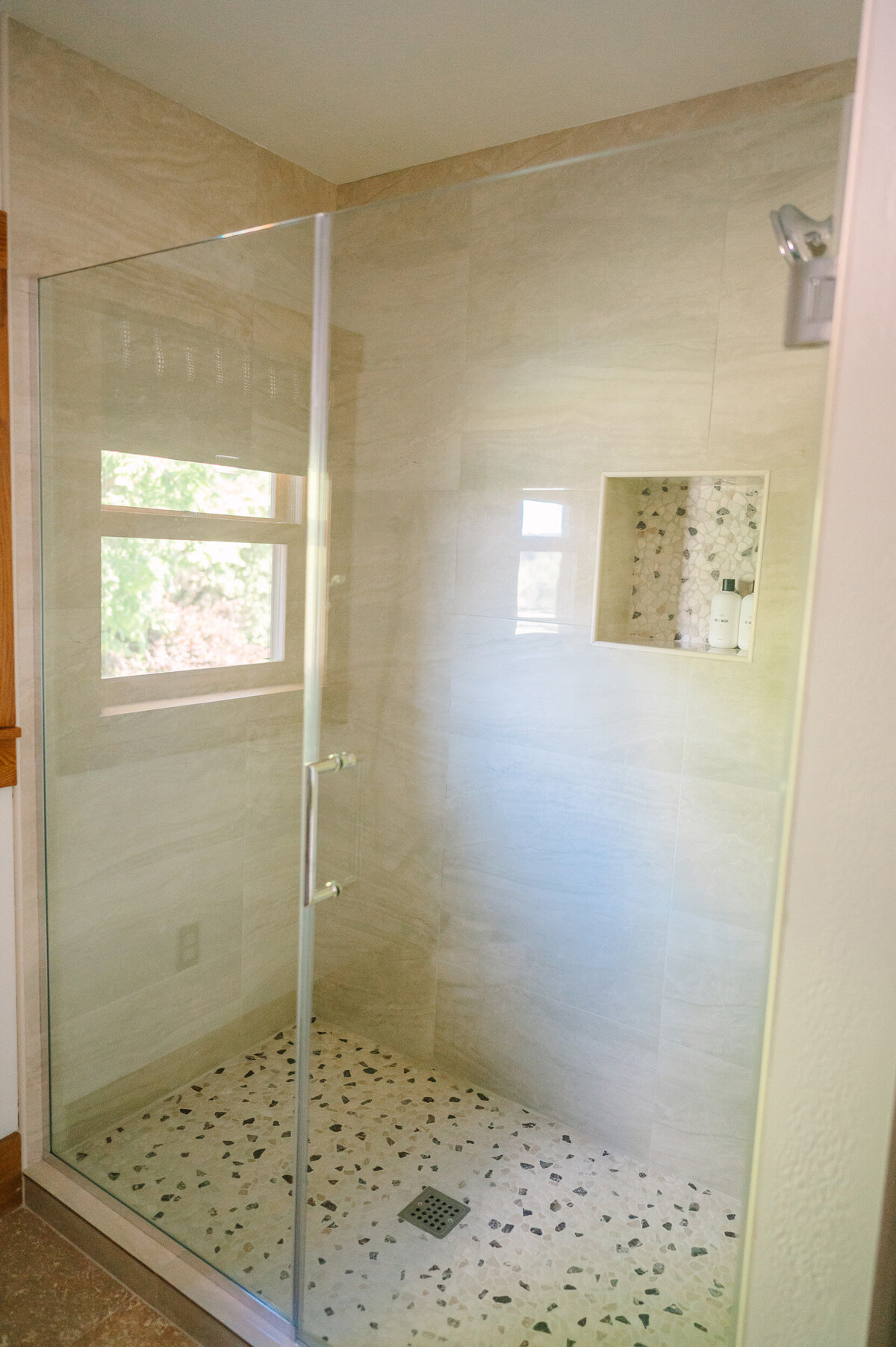 the travertine tile shower in the downstairs bathroom with tumbled stone floor tiles at the modern farmhouse overnight accommodations at Willowbrook wedding venue