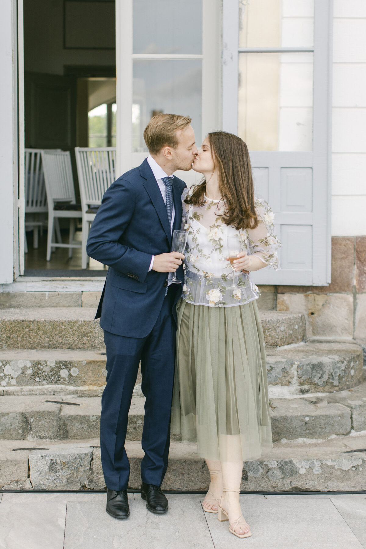 Bröllopsgäster pussas på terrassen på Schenströmska