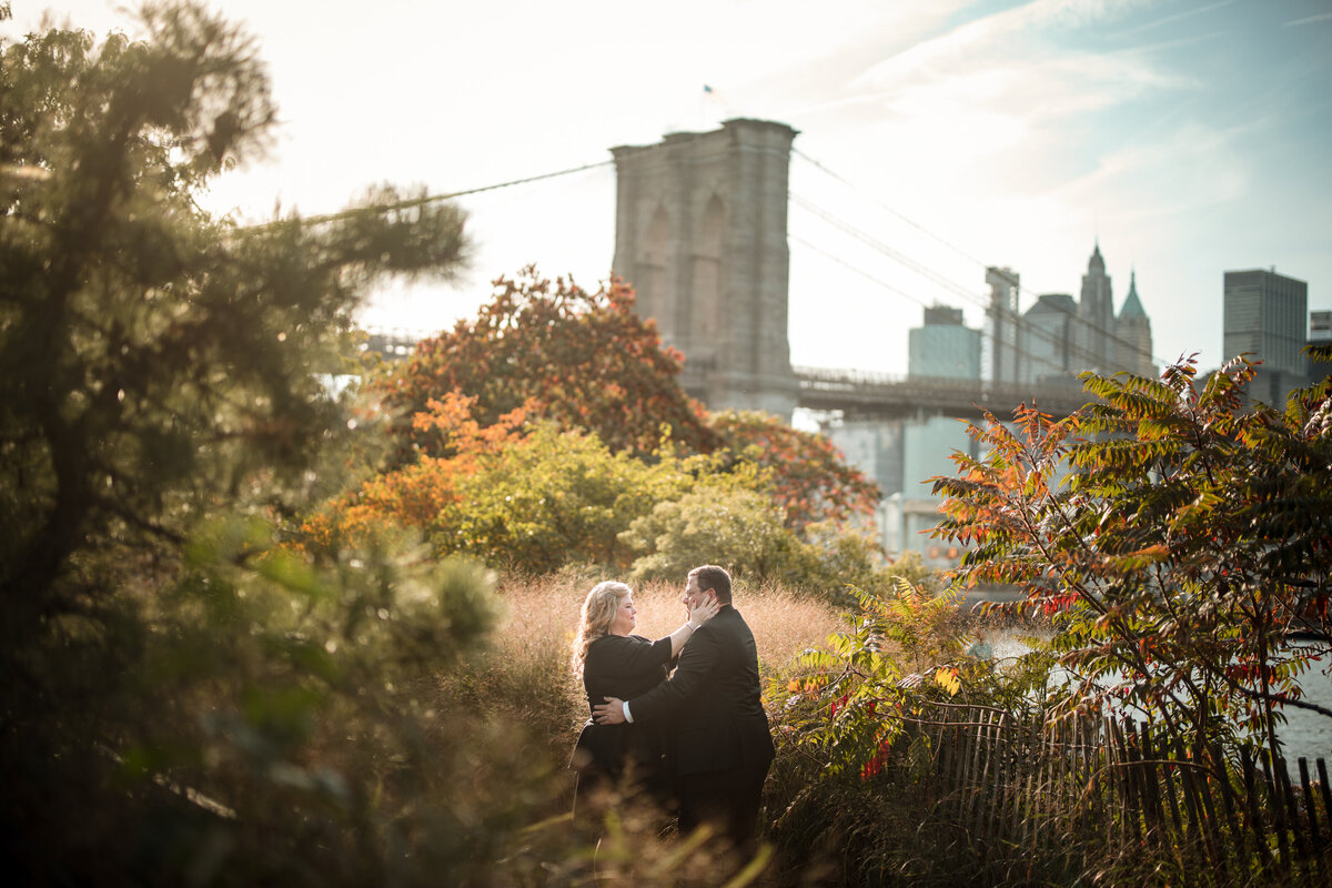 A man and woman standing in a park with a city skyline behind them.
