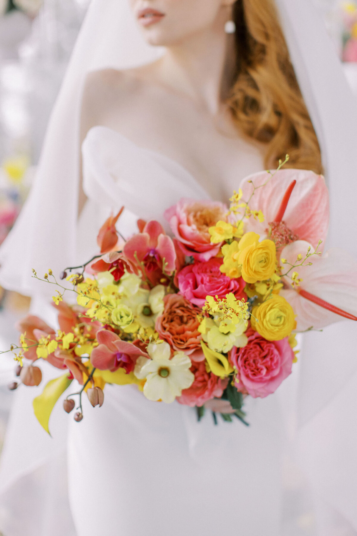 Bride in a white dress holds a colorful bouquet with pink, yellow, orange, and white flowers at an elegant wedding in Banff, Alberta.