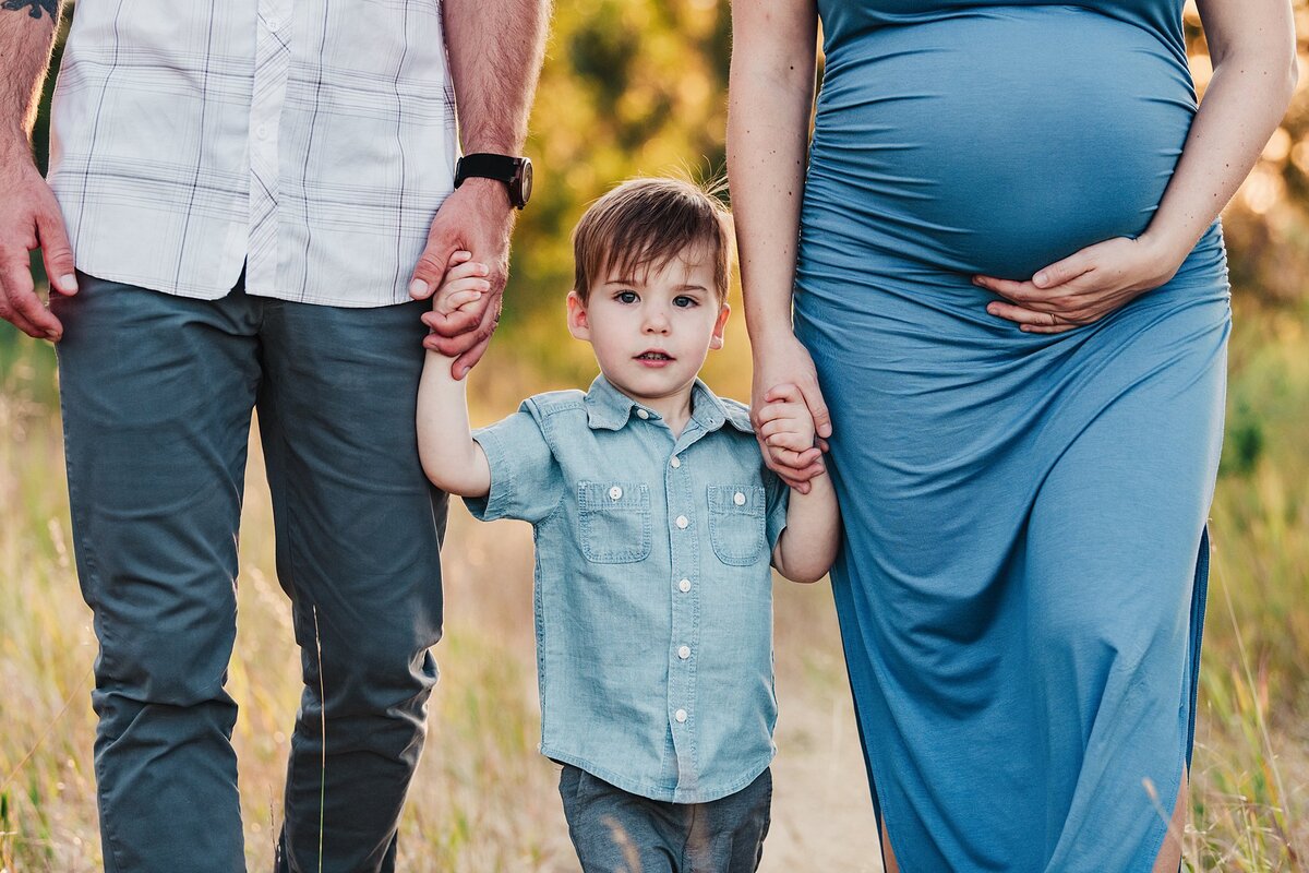 family maternity photography holding hands with toddler in the middle