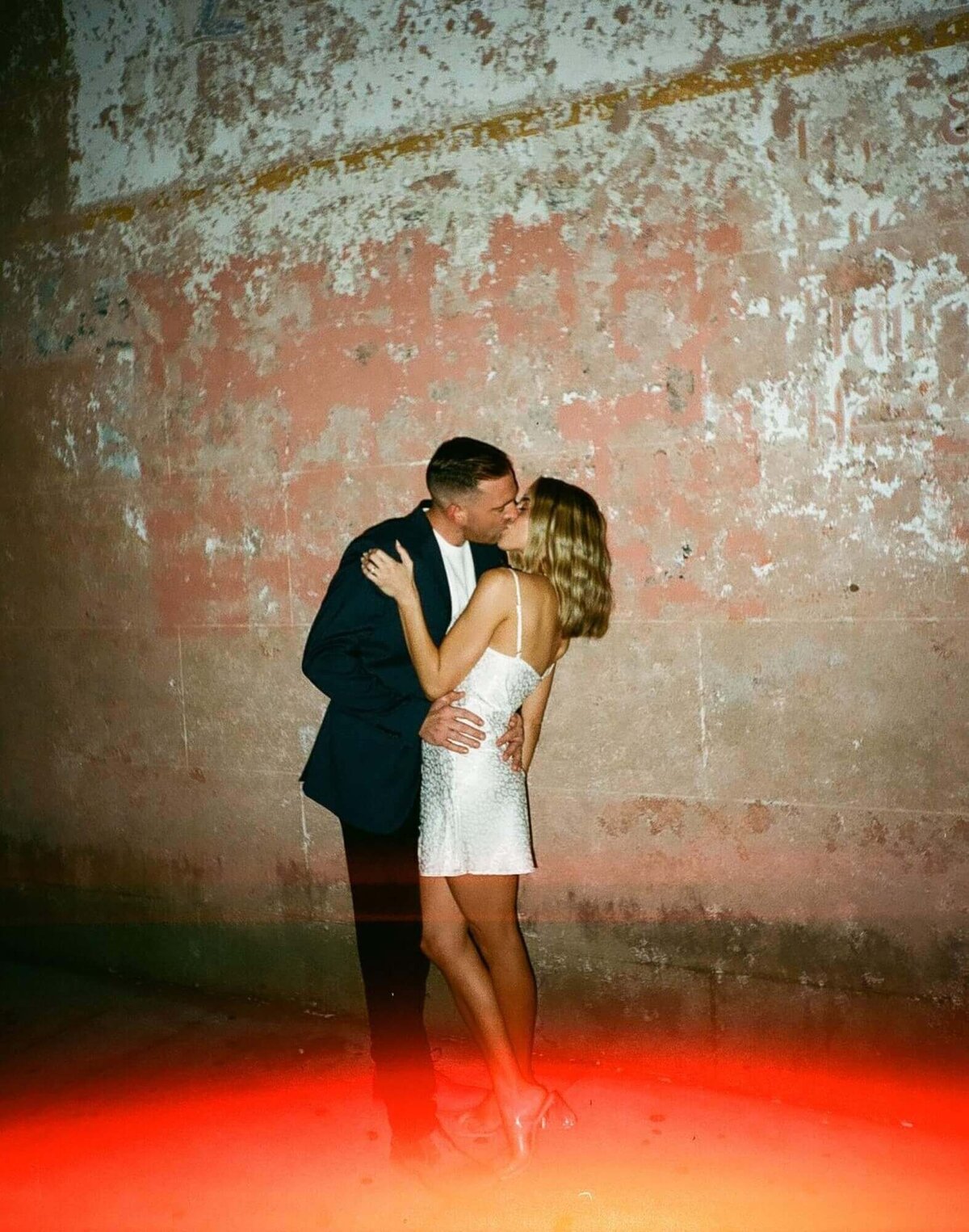 couple-kissing-nighttime-city-wall-film-flash