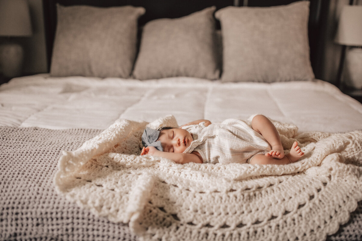 baby girl asleep in her crib with a flower mobile over her