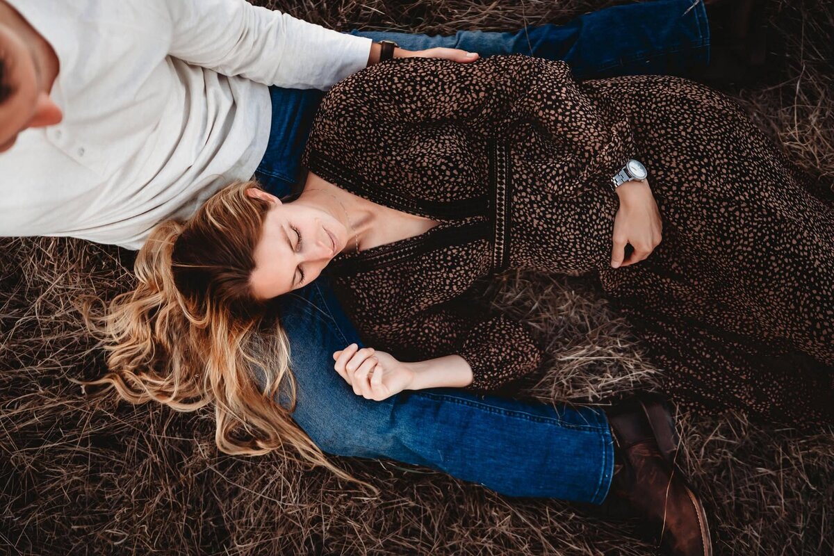 San Diego Maternity Photographer captures woman laying down with husband during beach maternity photos