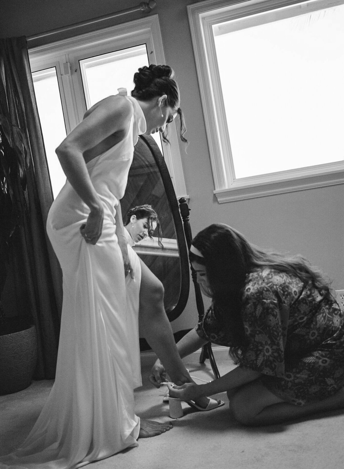 Bride puts on her wedding shoes in a quiet black and white getting ready moment — by Kate Winters Photography.