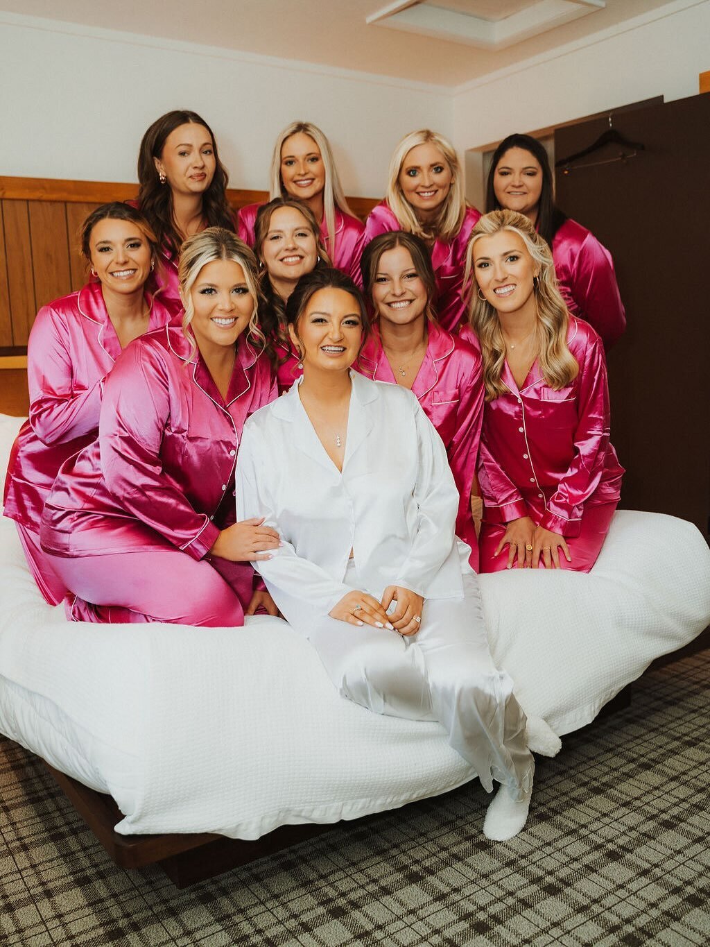 A bride and her bridal party pose together on a bed a they radiate in their glam and soak in the final moments before "I do!"