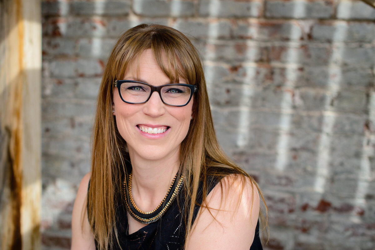 denver commercial photographer captures brand photography for small business owner of woman with glasses sitting in an outdoor space for her brand pictures