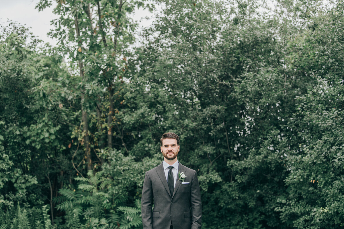 A groom wearing a grey suit posing for portraits