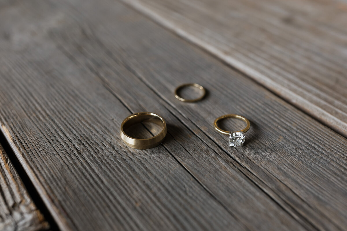 A close-up detail shot of wedding rings on rustic wooden planks, capturing the elegance of a Napa Valley wedding.
