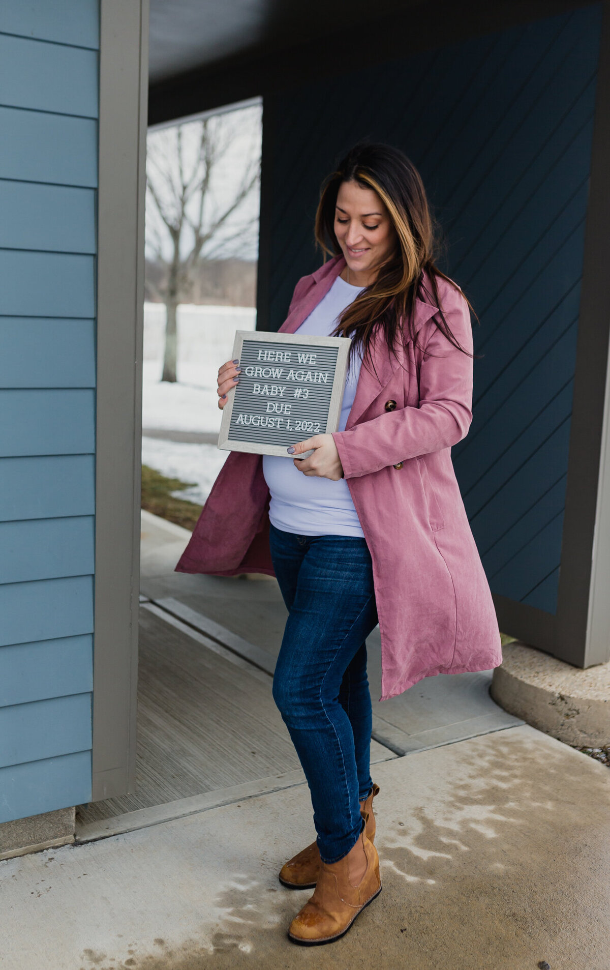 Pregnancy announcement with soon to be mom outside holding announcement board.n