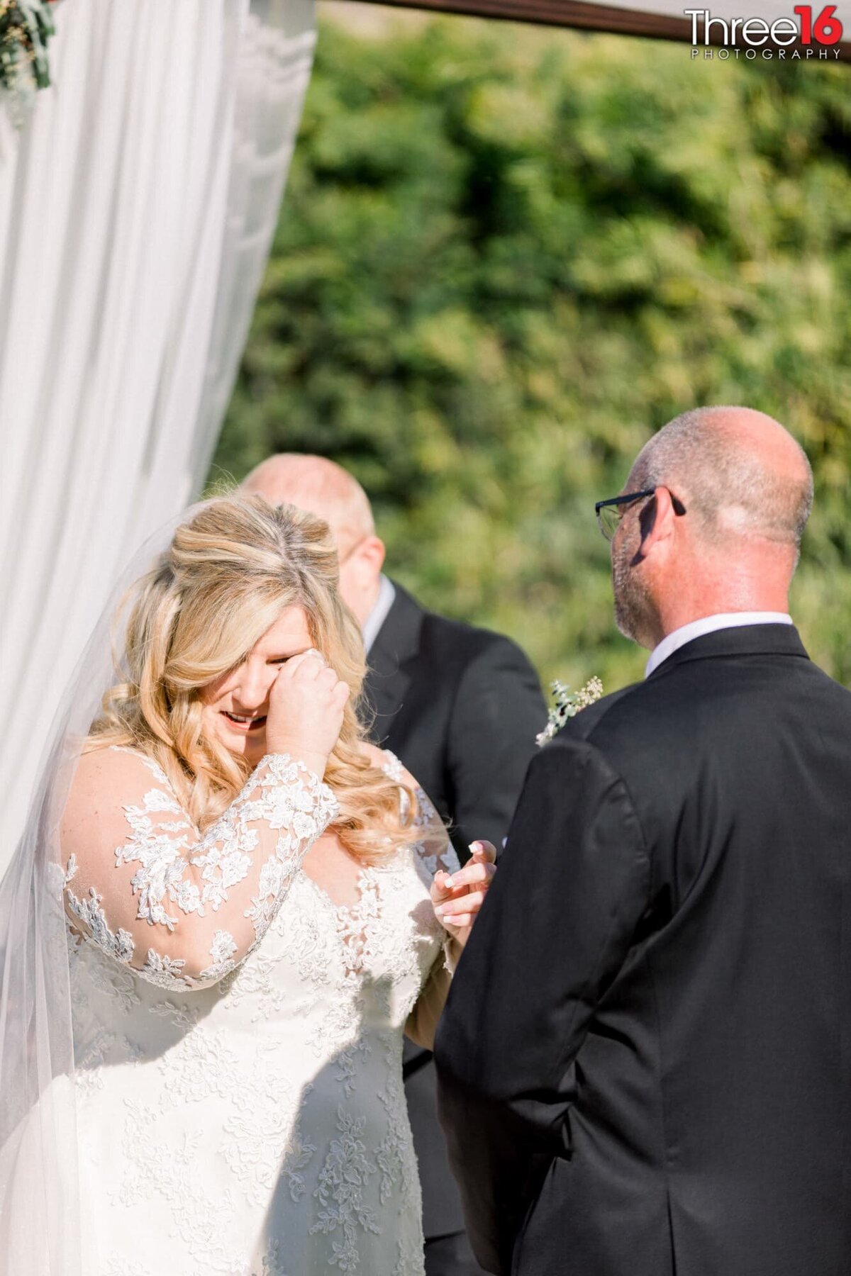 Bride wipes away a tear during the wedding ceremony
