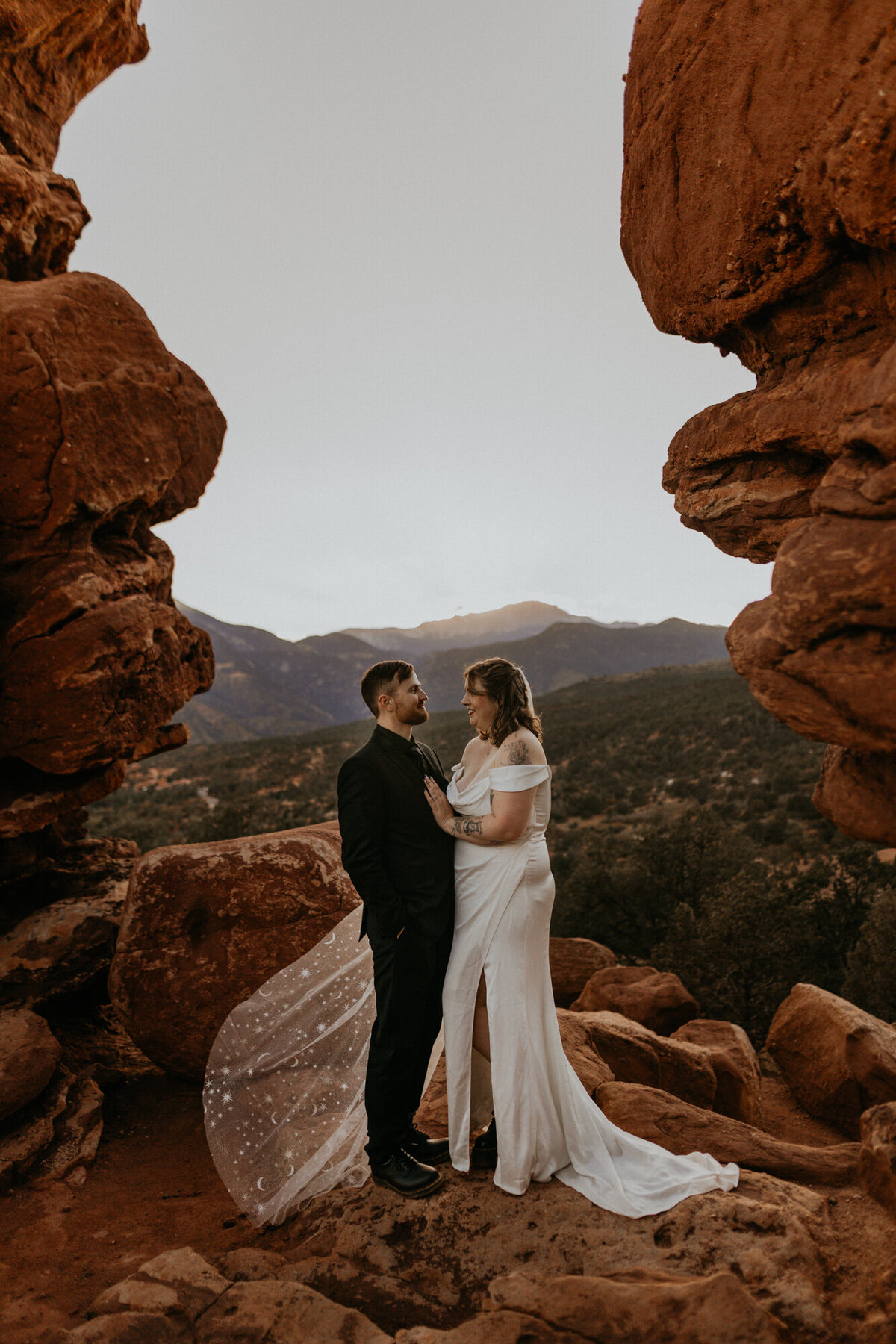 newlyweds standing between red rocks at Garden of the Gods in Colorado