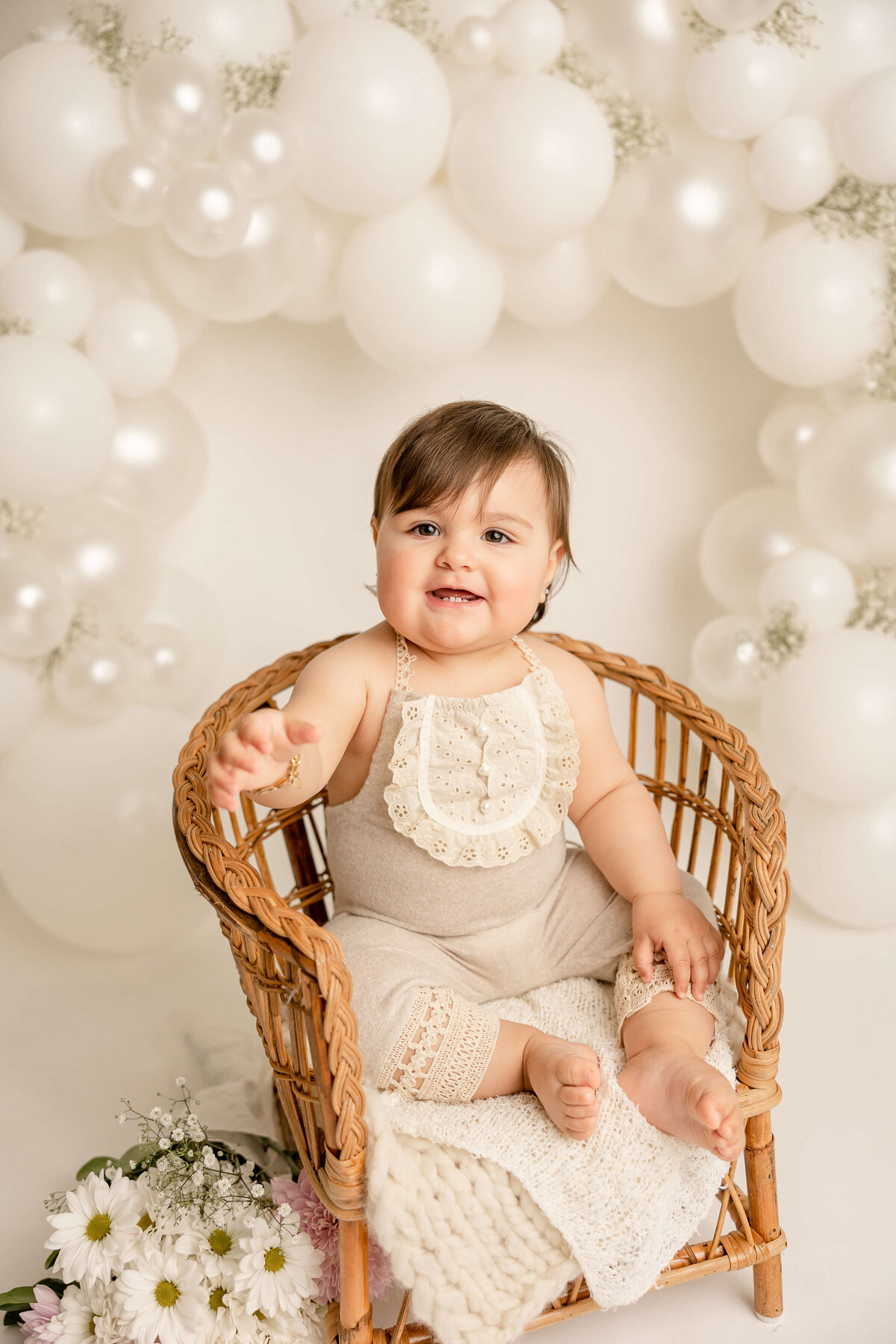 baby girl in cream romper sitting in chair in pdx for first birthday studio pictures
